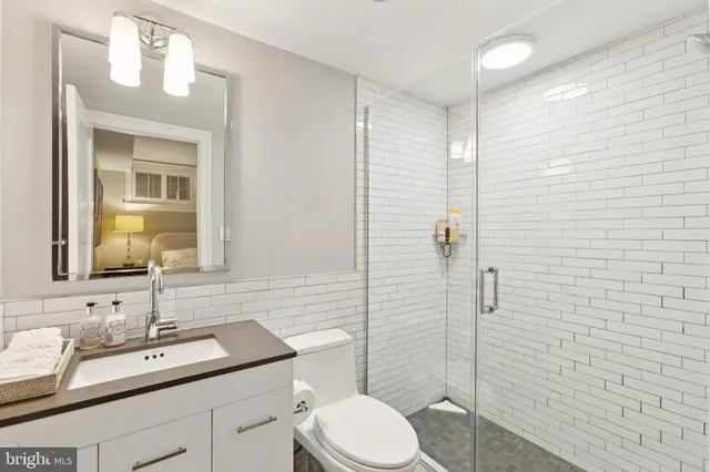 a bathroom with a granite countertop sink toilet a mirror and shower