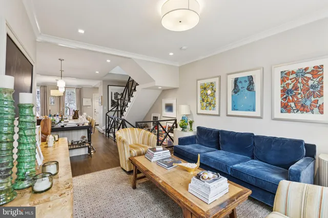 a living room with furniture kitchen view and a wooden floor