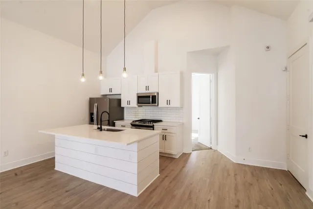 a kitchen with stainless steel appliances a stove top oven a refrigerator a sink and dishwasher with wooden floor