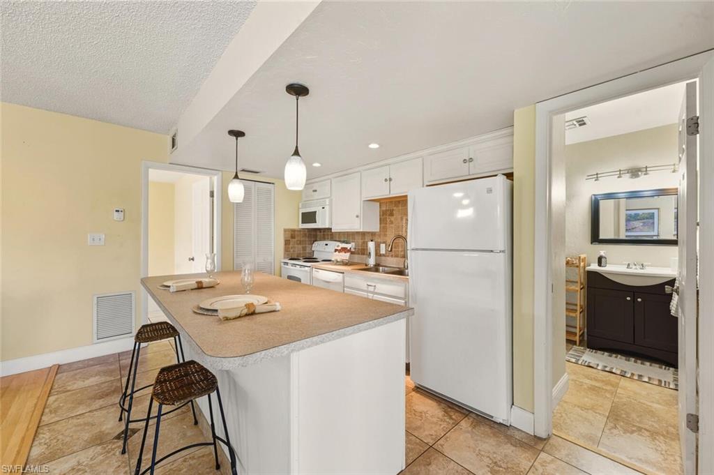 272 Palm Drive, Unit 2 Naples, FL 34112 - Photo 14 of 44 a kitchen with kitchen island a refrigerator a stove a sink a dining table and chairs