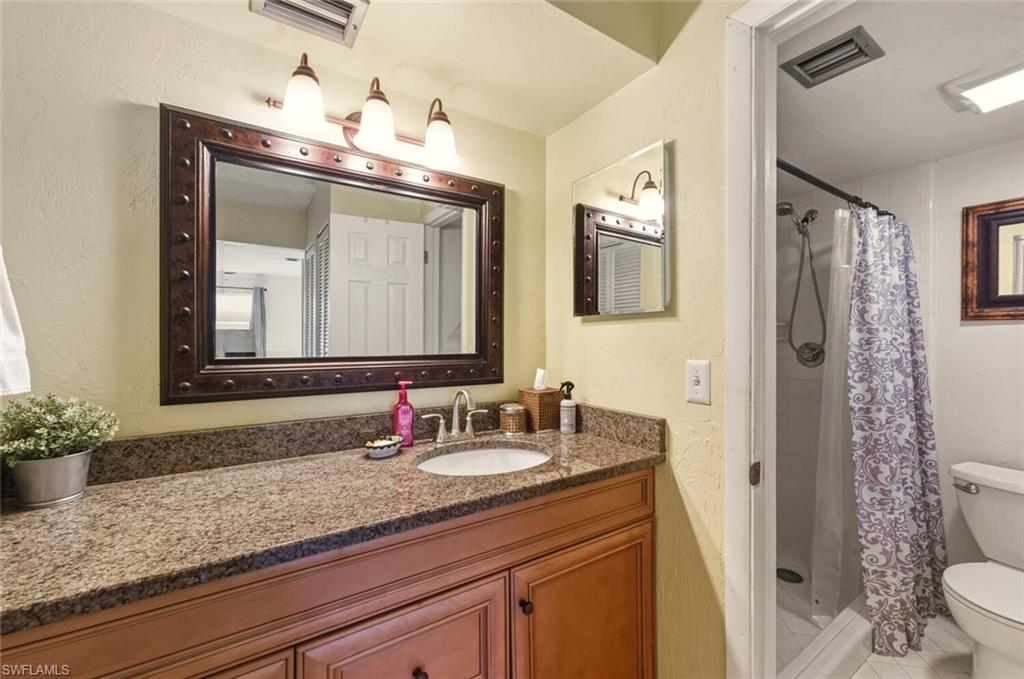 272 Palm Drive, Unit 2 Naples, FL 34112 - Photo 22 of 44 a bathroom with a granite countertop sink a toilet and mirror