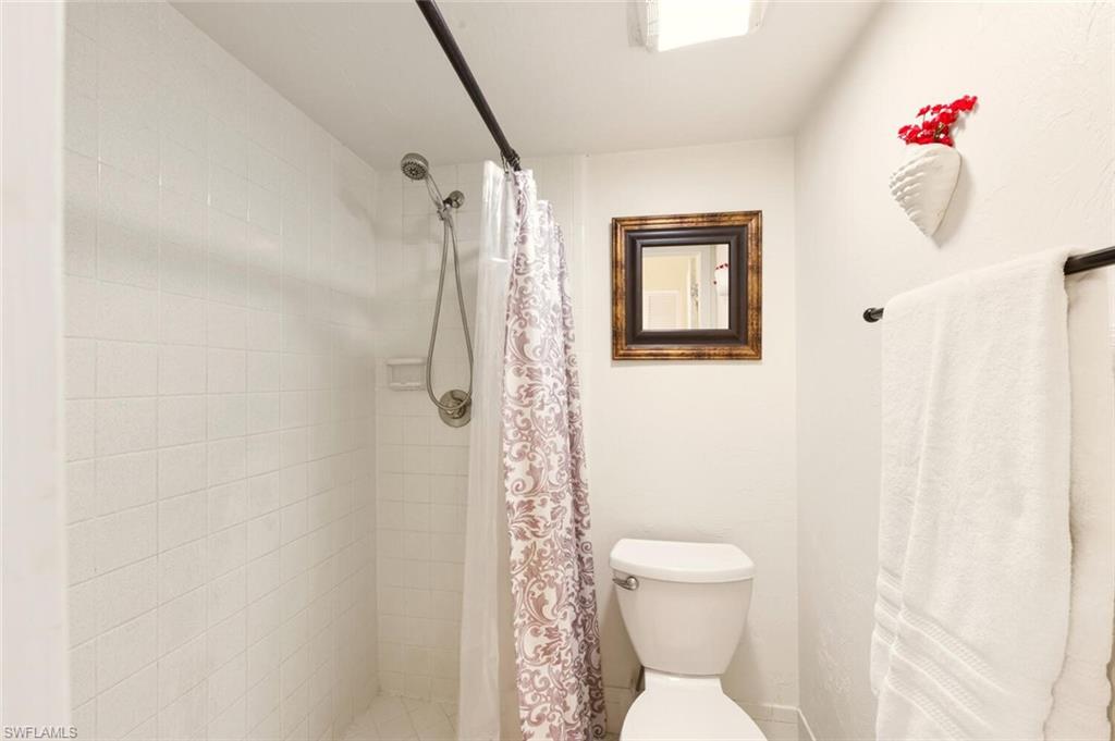 272 Palm Drive, Unit 2 Naples, FL 34112 - Photo 23 of 44 a bathroom with a toilet and shower curtain