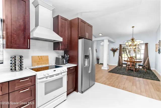 a kitchen with stainless steel appliances a stove a refrigerator a sink dishwasher with a dining table and chairs with wooden floor