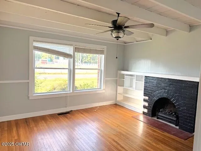 a view of empty room with wooden floor and fireplace