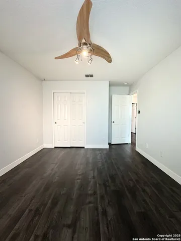 an empty room with wooden floor door and windows