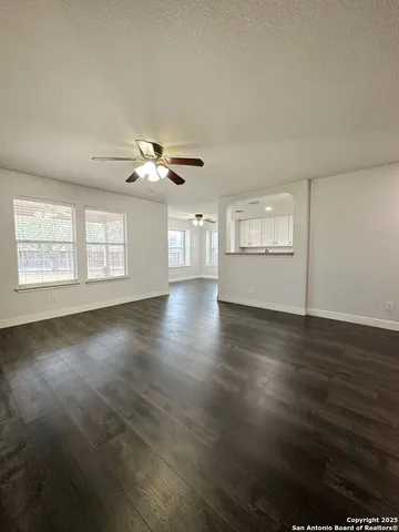 a view of an empty room with a window and wooden floor