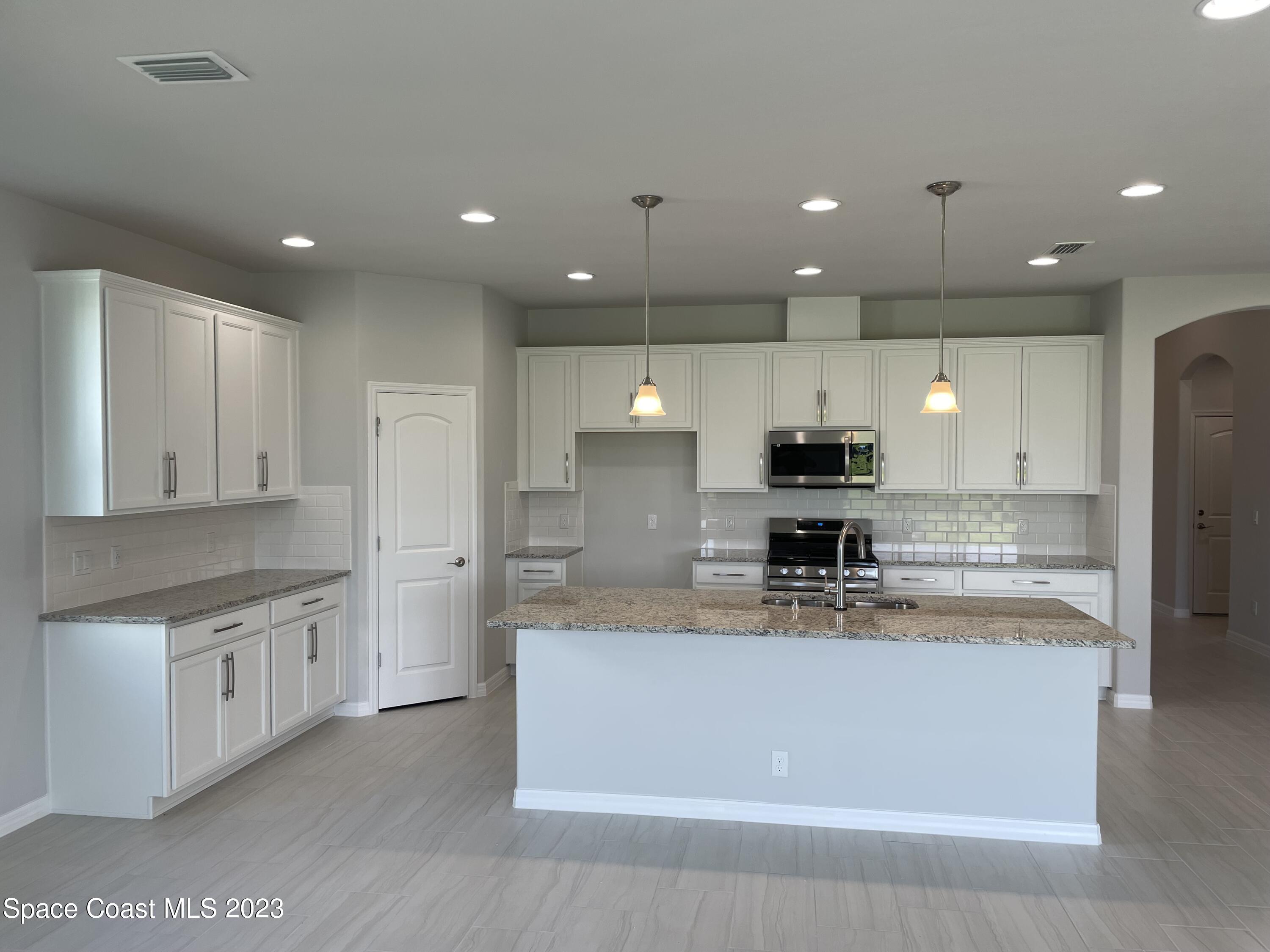3085 Zeler Place Melbourne, FL 32940 - Photo 2 of 16 a large kitchen with stainless steel appliances kitchen island a large counter top and a refrigerator