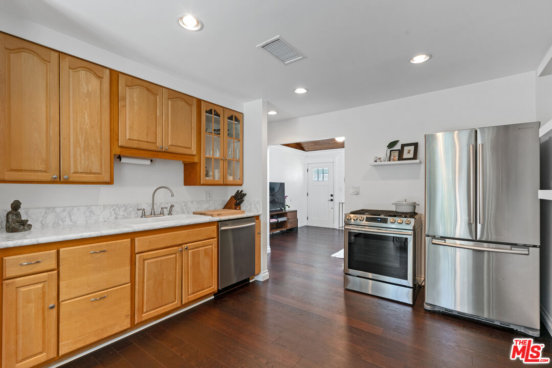 8000 Ramsgate Avenue Los Angeles, CA 90045 - Photo 3 of 23 a kitchen with stainless steel appliances granite countertop a refrigerator a sink dishwasher and white cabinets with wooden floor