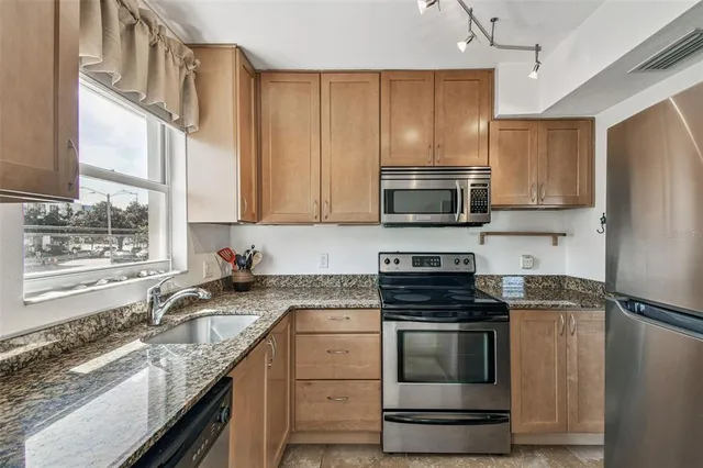 a kitchen with stainless steel appliances granite countertop a refrigerator stove and sink