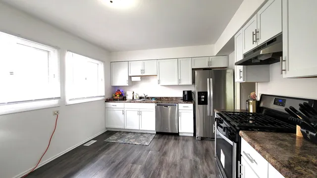 a kitchen with a sink wooden floor and stainless steel appliances