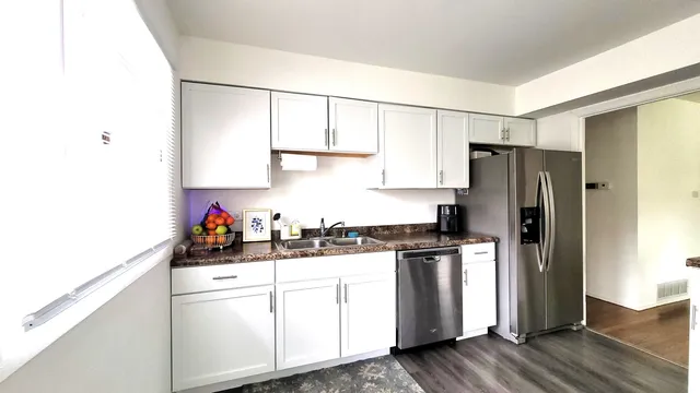 a kitchen with a sink a refrigerator and white cabinets