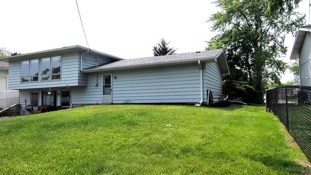 a backyard of a house with plants and large tree