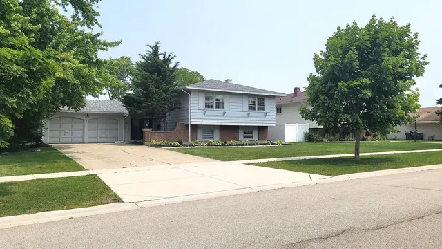 a view of a house with a yard and large trees