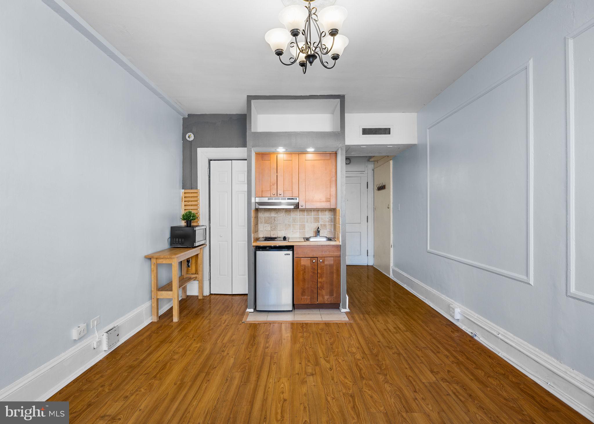 1324 Locust Street, Unit 807 Philadelphia, PA 19107 - Photo 18 of 36 a kitchen with stainless steel appliances wooden floor and chandelier