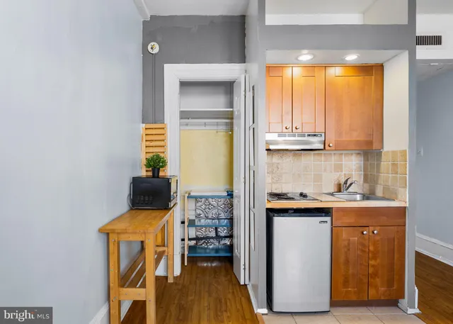 a kitchen with a sink a stove cabinets and wooden floor