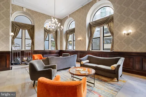 a living room with furniture a chandelier and a large mirror