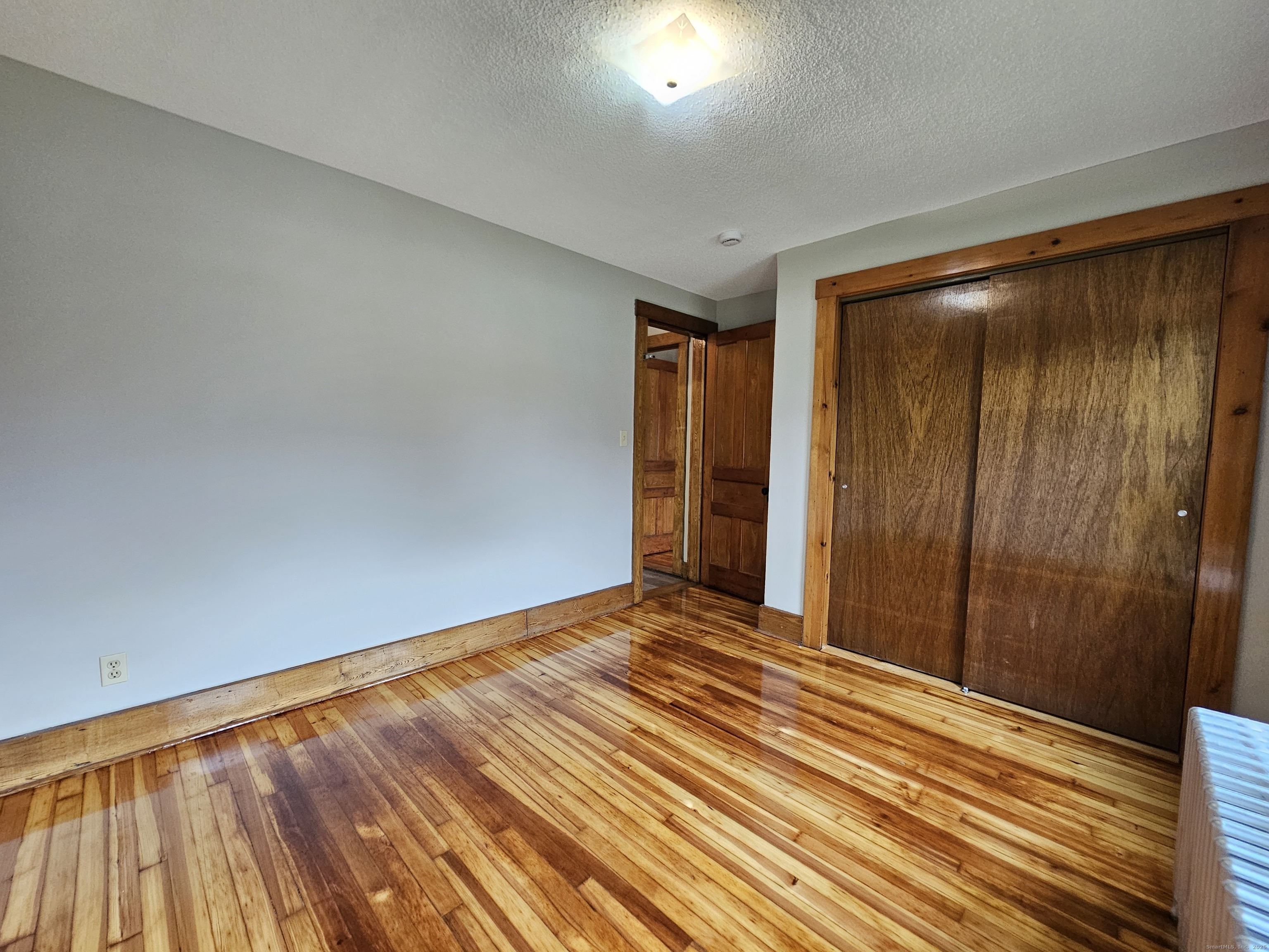 581 Center Street, Unit 1 Wallingford, CT 06492 - Photo 13 of 14 a view of an empty room with wooden floor and a window