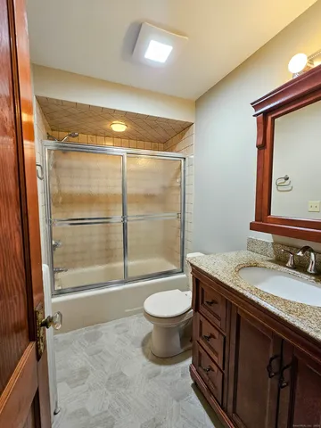 a bathroom with a granite countertop sink toilet and shower