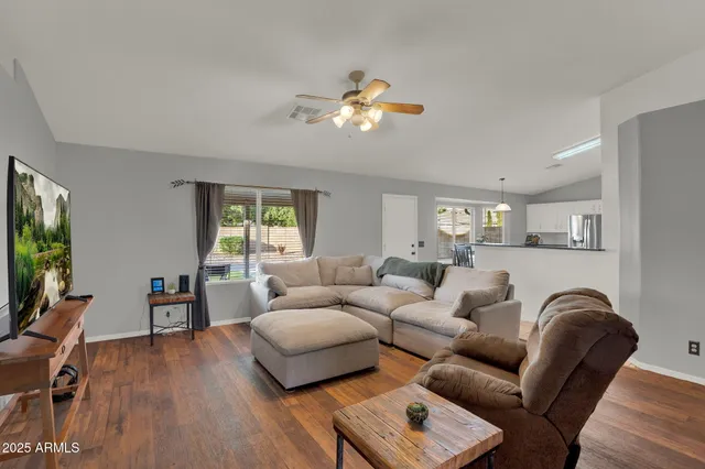 a living room with furniture a ceiling fan and a flat screen tv