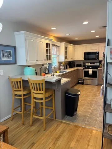 a kitchen with stainless steel appliances granite countertop a table chairs sink and cabinets