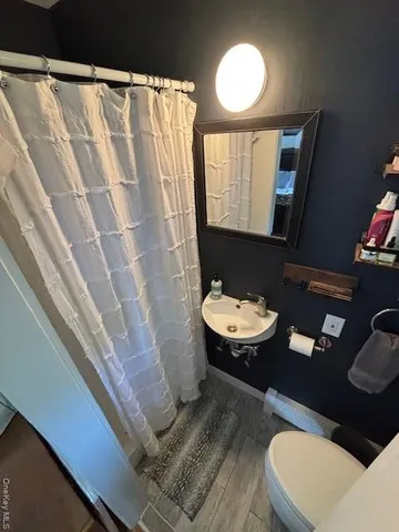 a bathroom with a sink a toilet a mirror and shower curtain