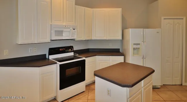 a kitchen with white cabinets and white appliances