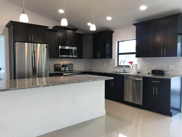 a kitchen with stainless steel appliances granite countertop a refrigerator a sink a stove a microwave and a refrigerator