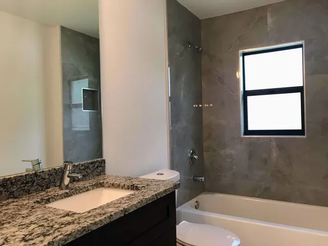 a bathroom with a granite countertop tub sink and mirror