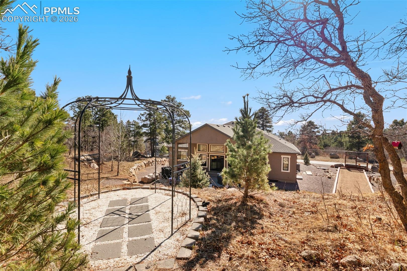 5318 Rocking Tree Grove Colorado Springs, CO 80906 - Photo 41 of 49 Winding pathways lead to a secluded garden gazebo, offering a tranquil destination on the property for morning coffee or quiet reflection surrounded by nature