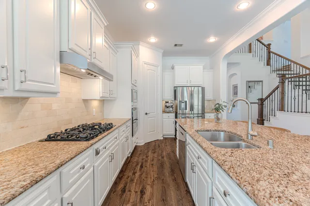 a kitchen with stainless steel appliances granite countertop a sink refrigerator and cabinets