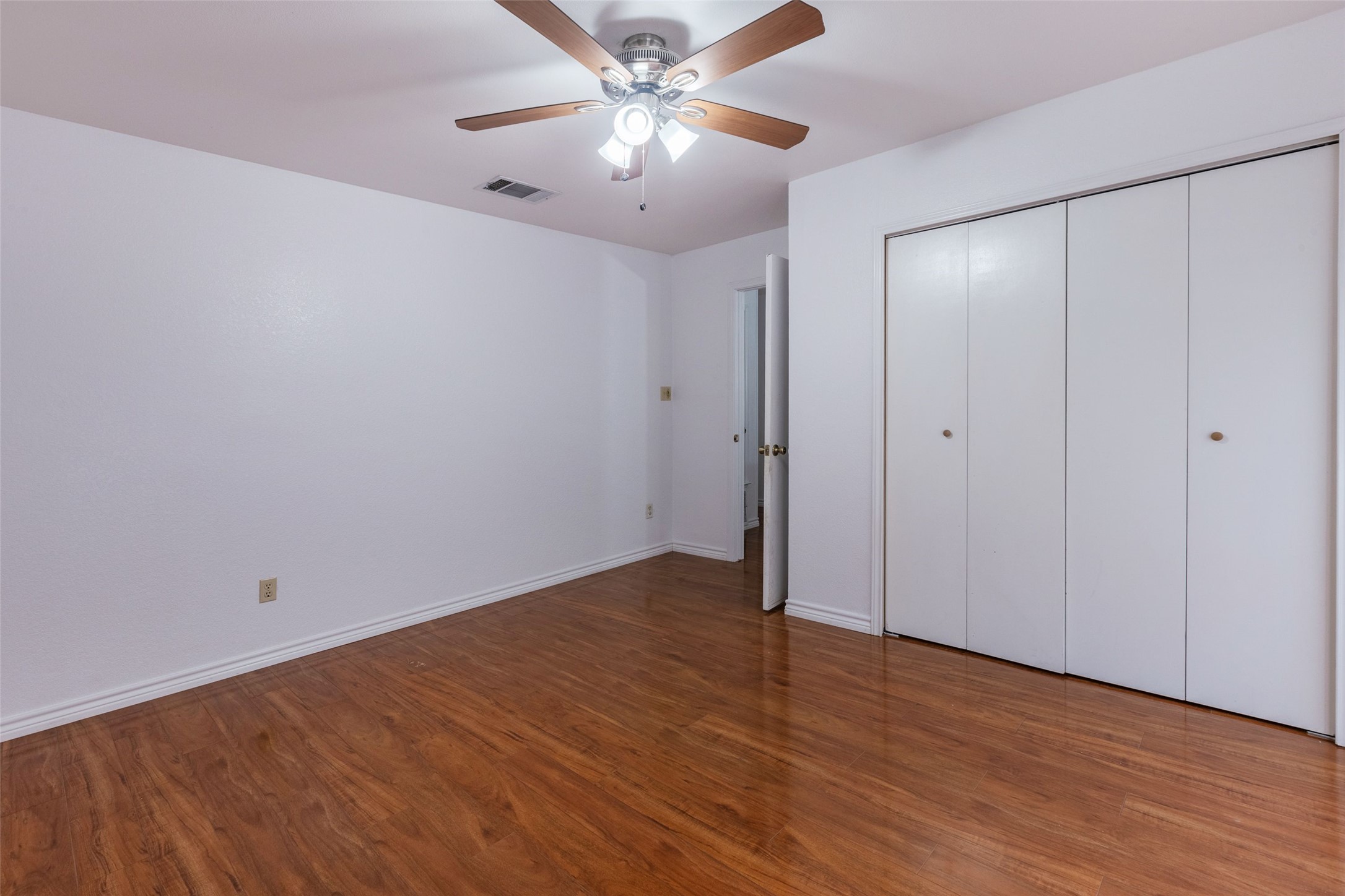 8506 Bisbee Court Austin, TX 78745 - Photo 13 of 20 Spacious room featuring wood-finish flooring, white walls, and a ceiling fan with integrated lighting