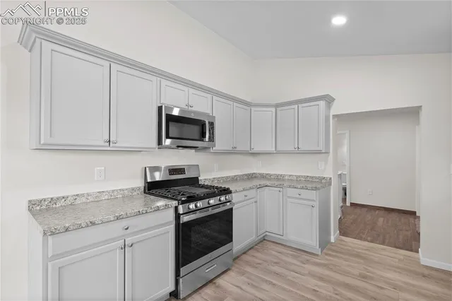 a kitchen with granite countertop white cabinets stainless steel appliances and a sink