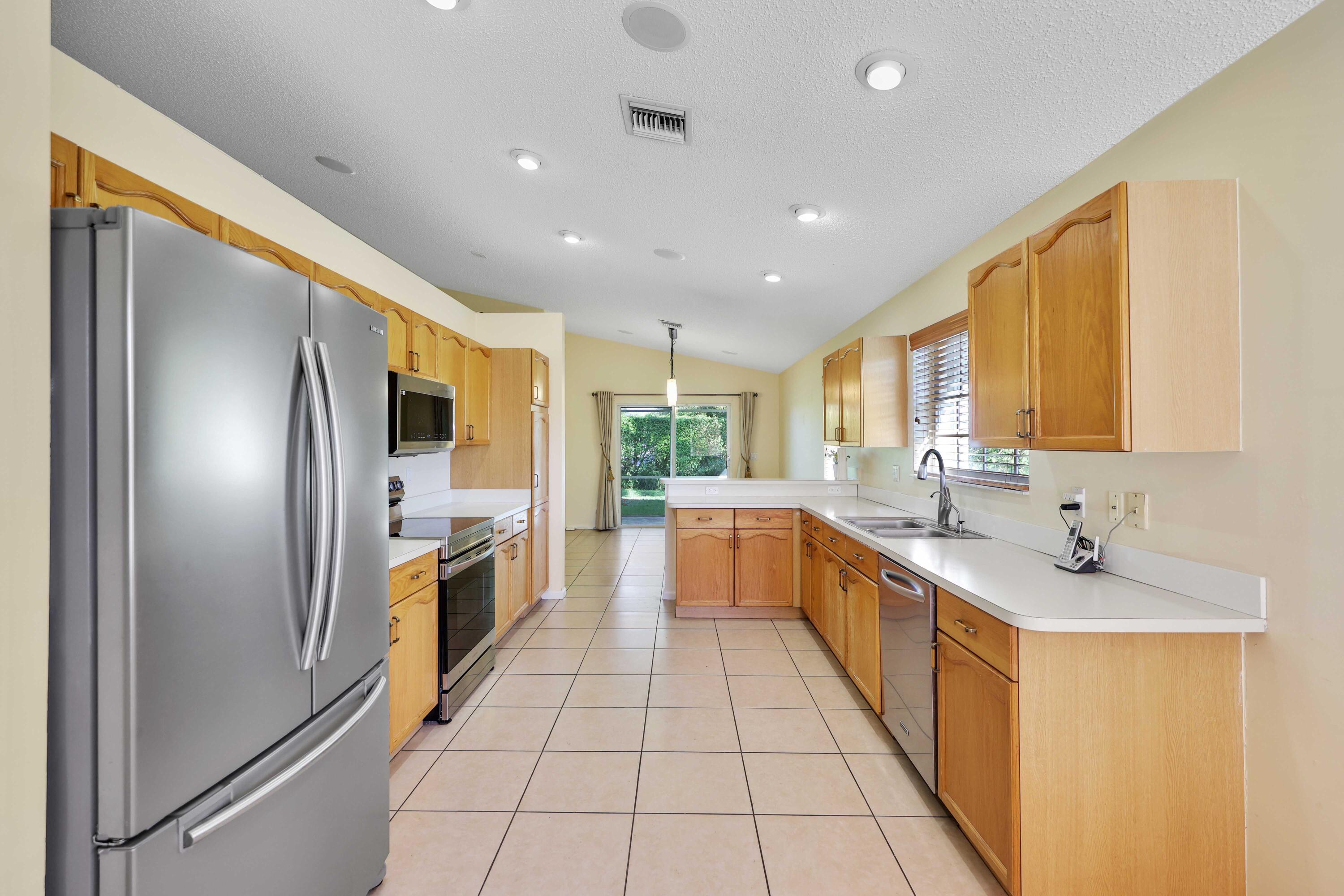 5125 Columbo Court Delray Beach, FL 33484 - Photo 20 of 60 a large kitchen with stainless steel appliances lots of counter space and windows