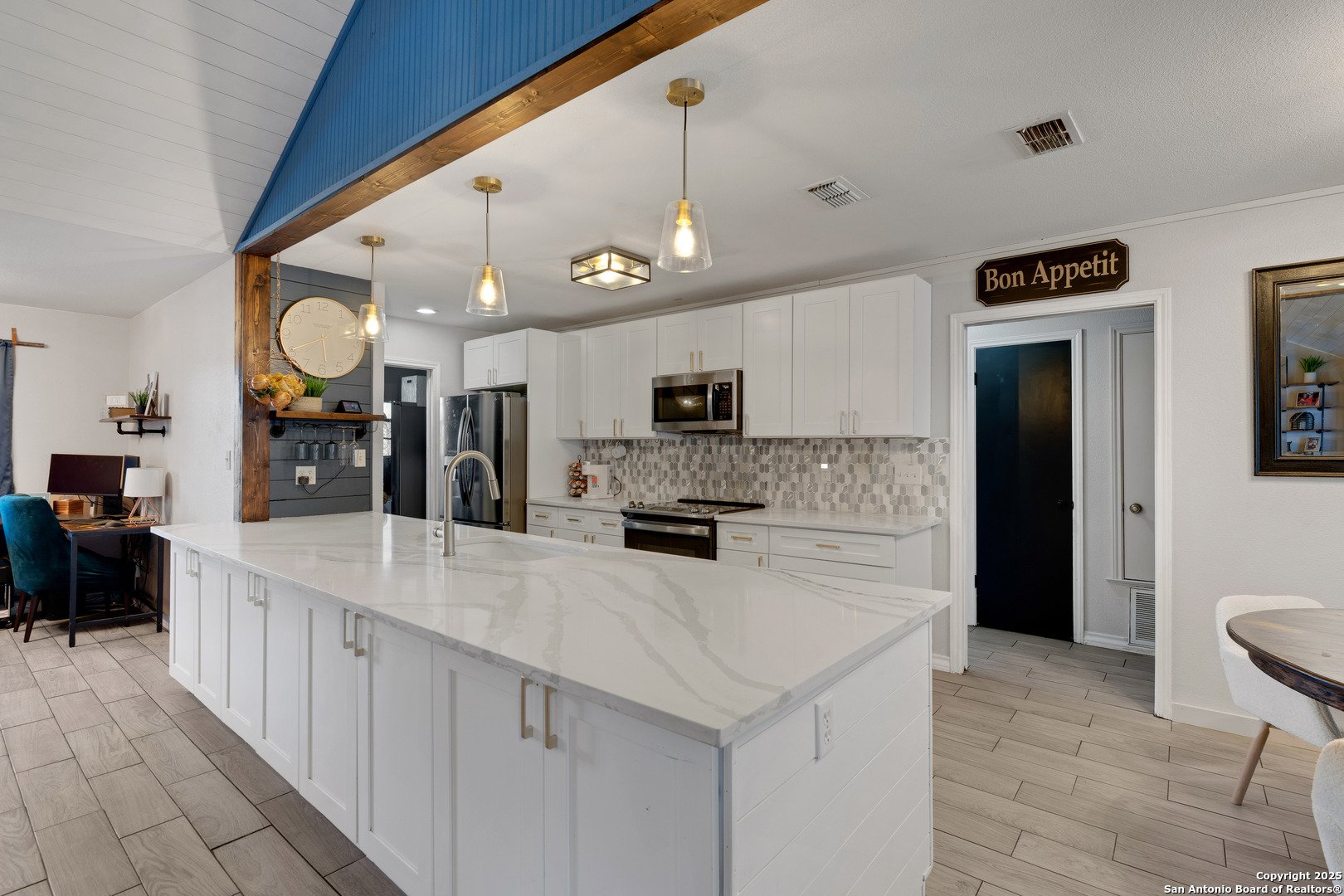 2665 Casey Road Bulverde, TX 78163 - Photo 13 of 42 a large white kitchen with a large island oven a stove a dining table and chairs with wooden floor