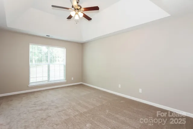 an empty room with windows and fan