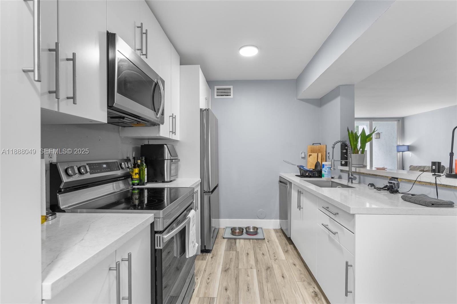 4624 Northwest 97th Place, Unit 252 Doral, FL 33178 - Photo 13 of 28 a kitchen with stainless steel appliances granite countertop a sink a stove top oven a refrigerator with white cabinets and wooden floor