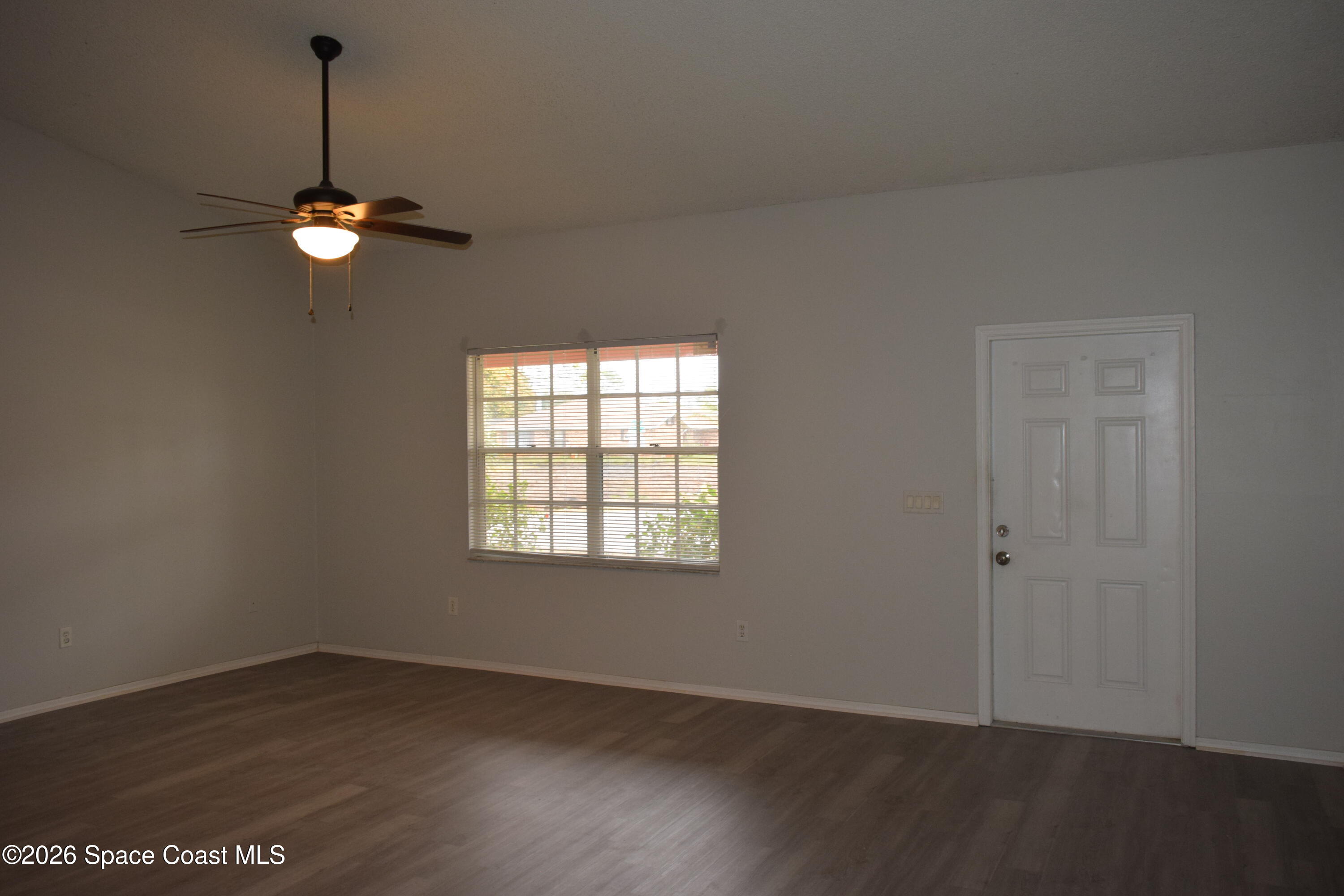 213 Abello Road Southeast Palm Bay, FL 32909 - Photo 3 of 23 an empty room with wooden floor ceiling fan and window