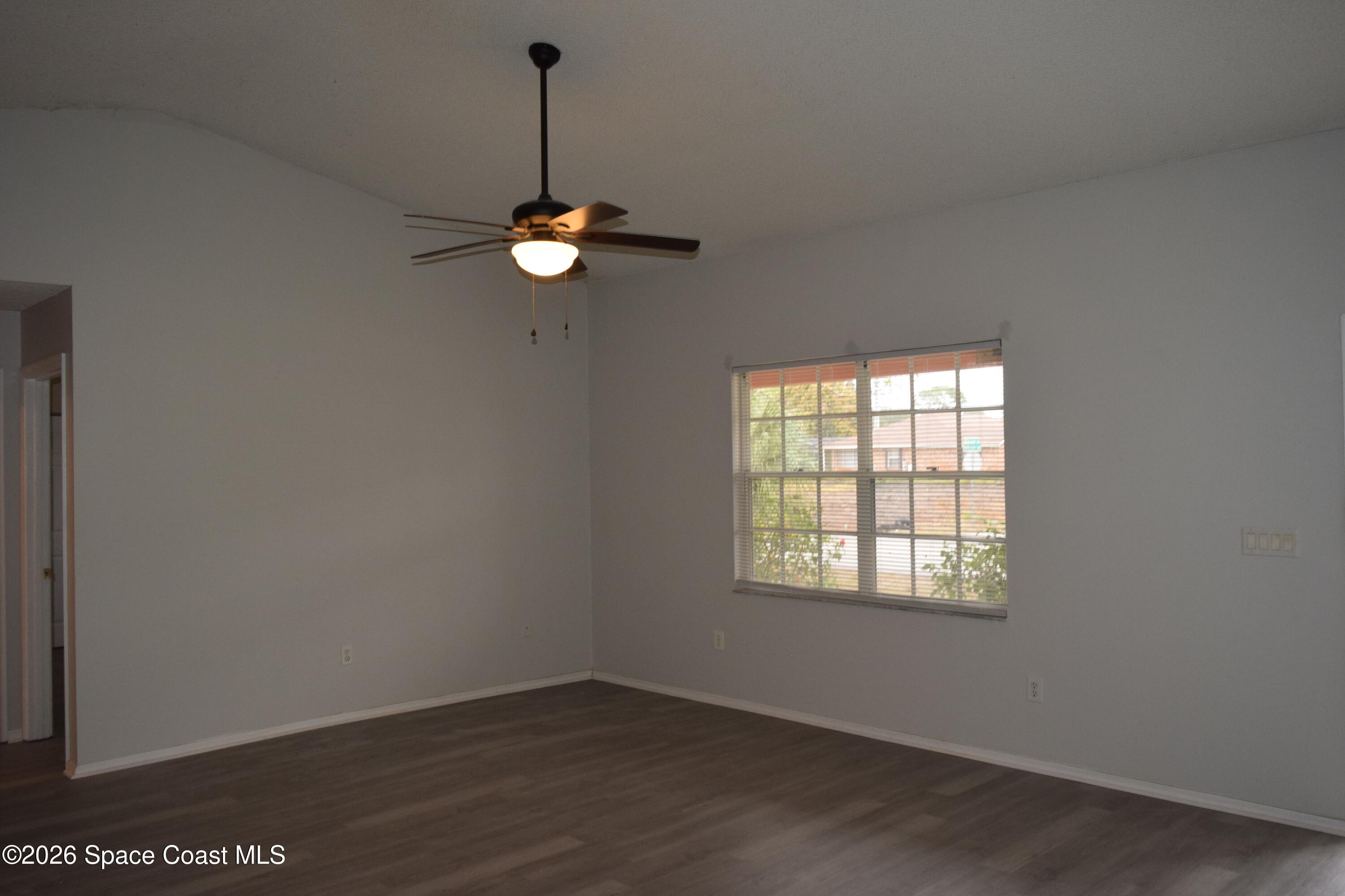 213 Abello Road Southeast Palm Bay, FL 32909 - Photo 4 of 23 an empty room with wooden floor a ceiling fan and windows