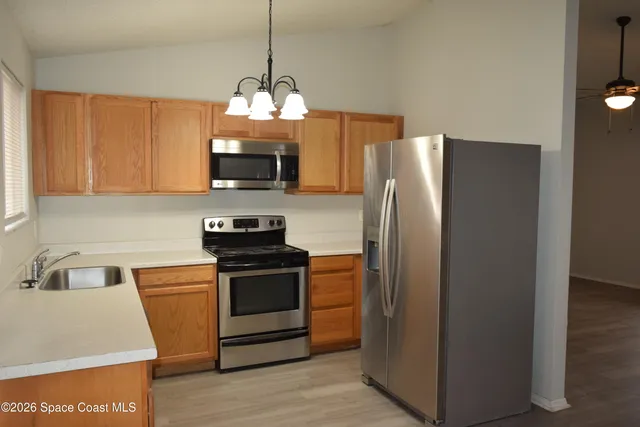 a kitchen with stainless steel appliances granite countertop a refrigerator a sink a stove and a microwave