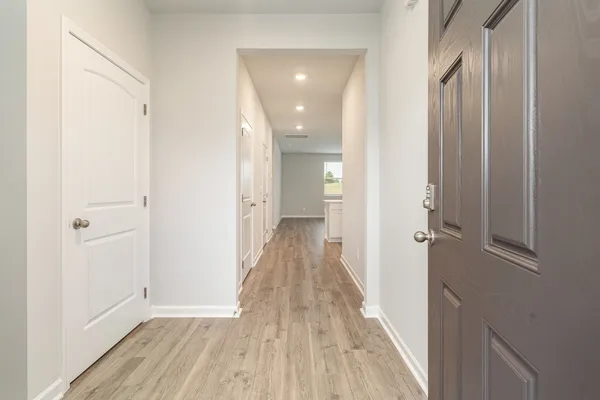 a view of a hallway with wooden floor and a bathroom