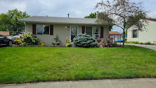 a front view of a house with a garden and trees