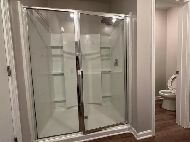 a bathroom with a glass door shower and a toilet