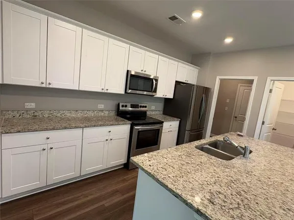 a kitchen with granite countertop a refrigerator stove and sink