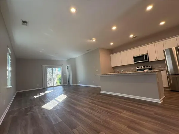 a view of empty room with wooden floor and electronic appliances