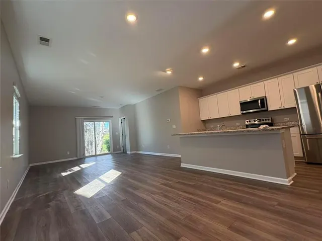 a view of empty room with wooden floor and electronic appliances