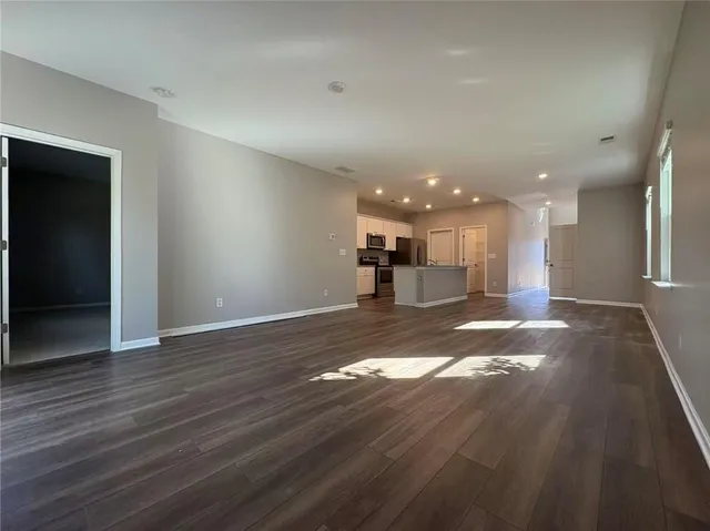 a view of a big room with wooden floor and a kitchen