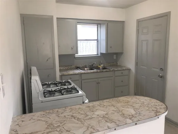 a kitchen with a stove a sink and a window