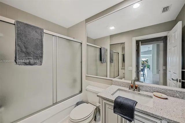 a bathroom with a granite countertop sink mirror vanity and toilet