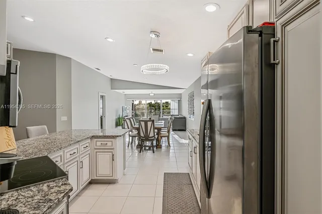 a kitchen with stainless steel appliances kitchen island granite countertop a refrigerator and a sink