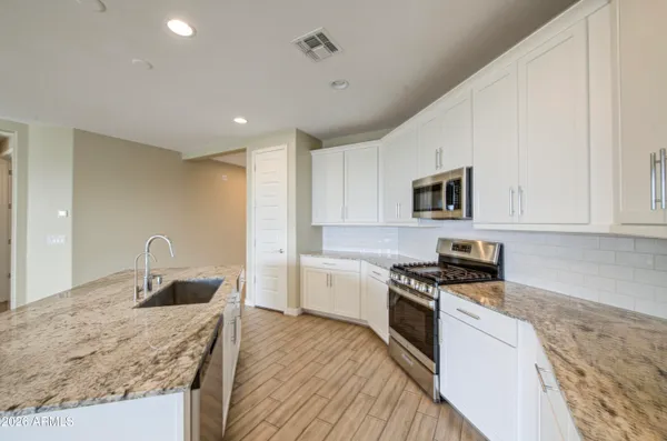 a kitchen with granite countertop a stove a sink and a microwave